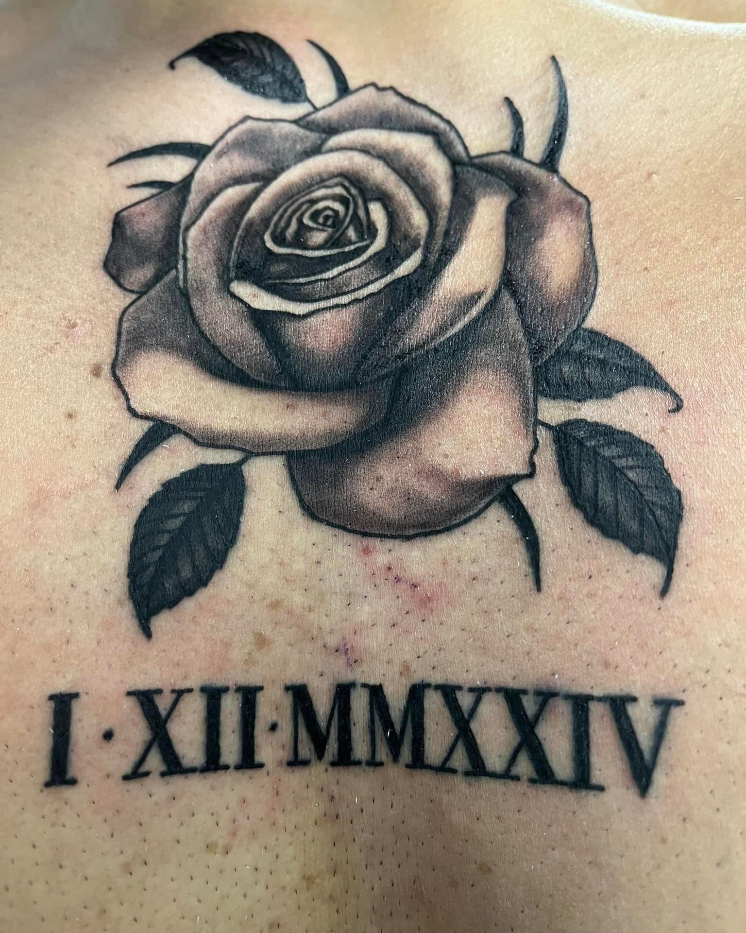 A tattoo of a rose and roman numerals on a person 's back