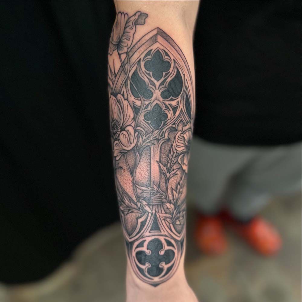 A person has a tattoo of a stained glass window on their forearm