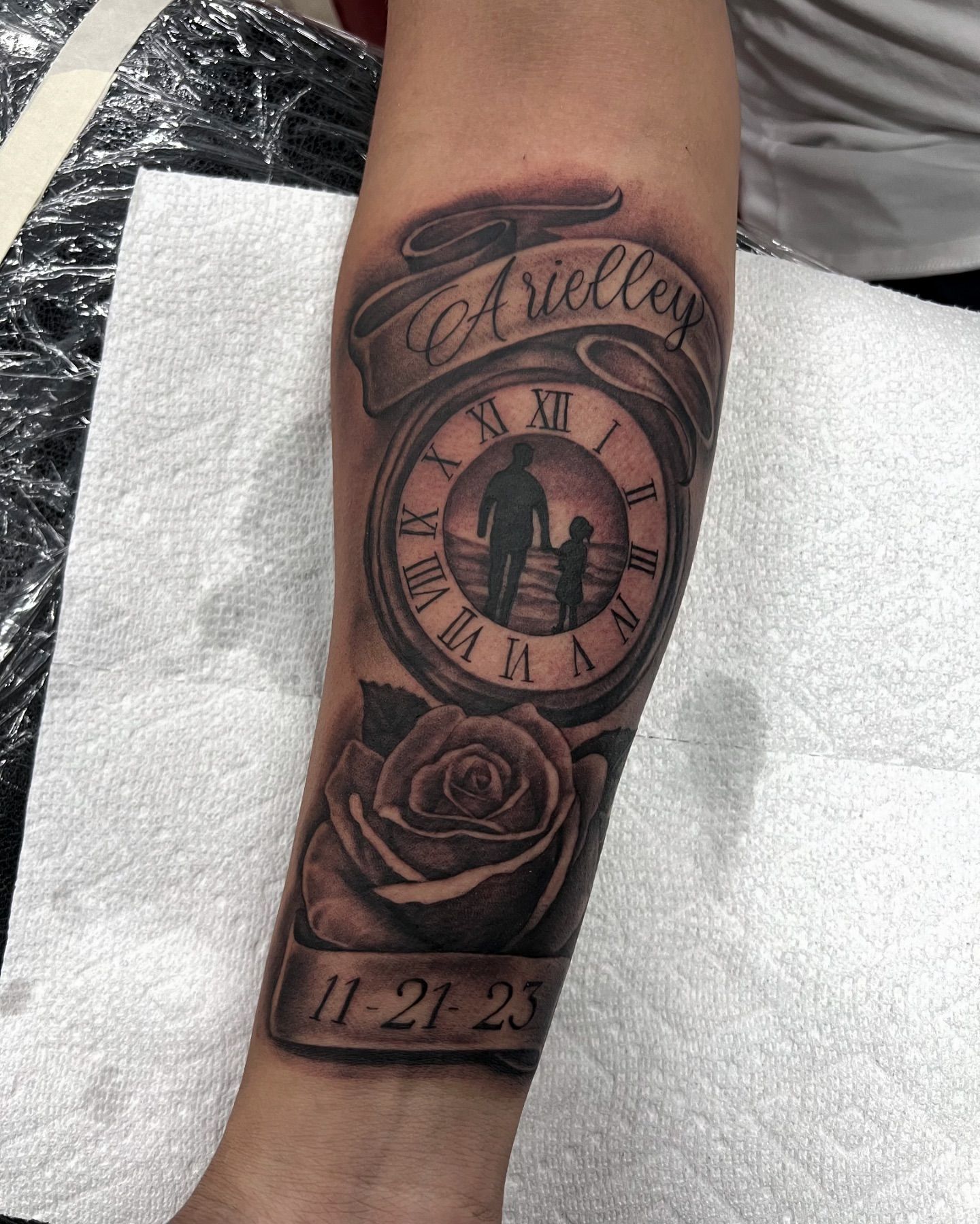 A man has a tattoo of a clock and a rose on his forearm.