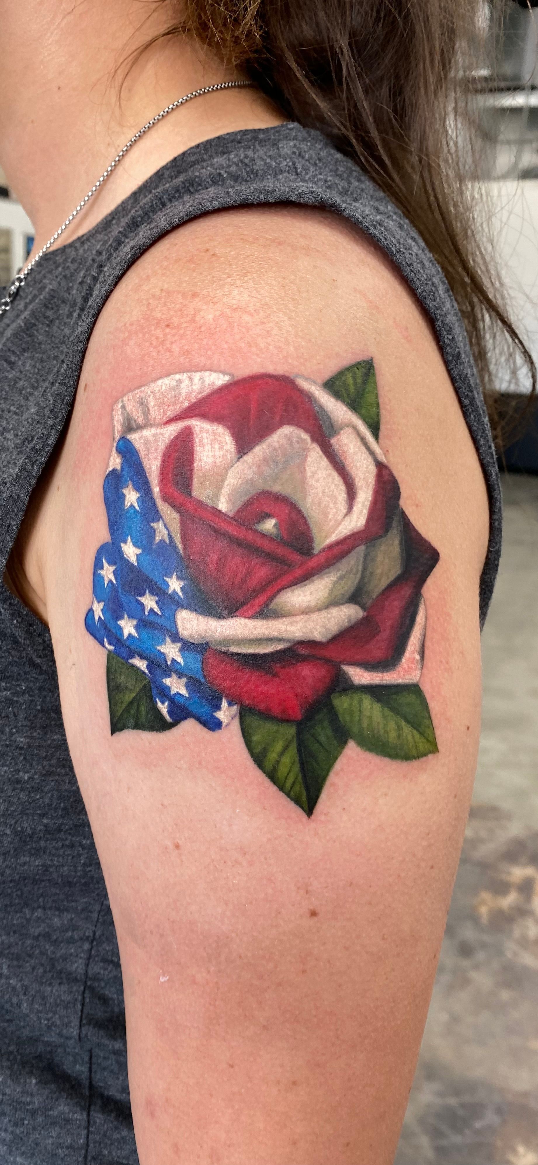 Tattoo of a rose with a USA flag design on a person's arm.