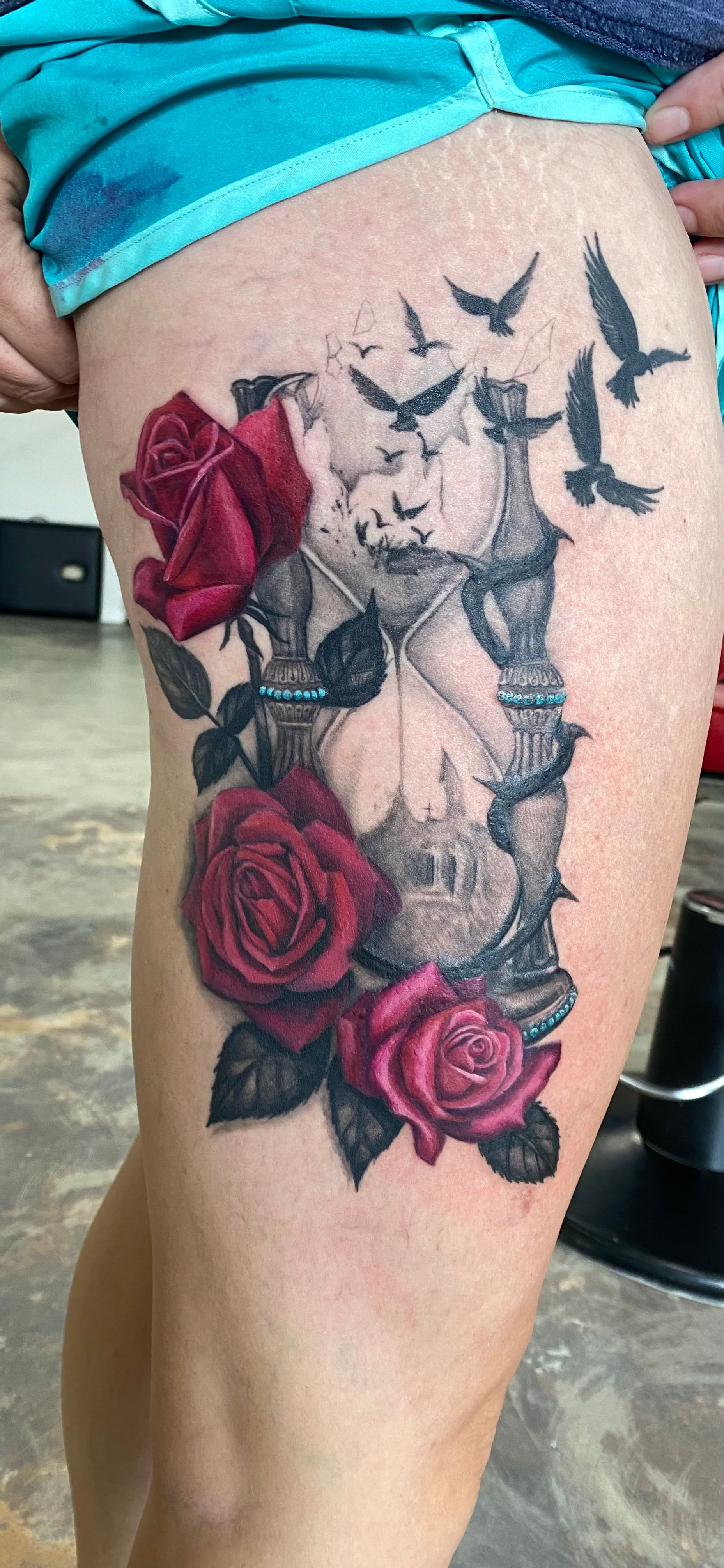 Tattoo on a leg: hourglass, roses, and birds.