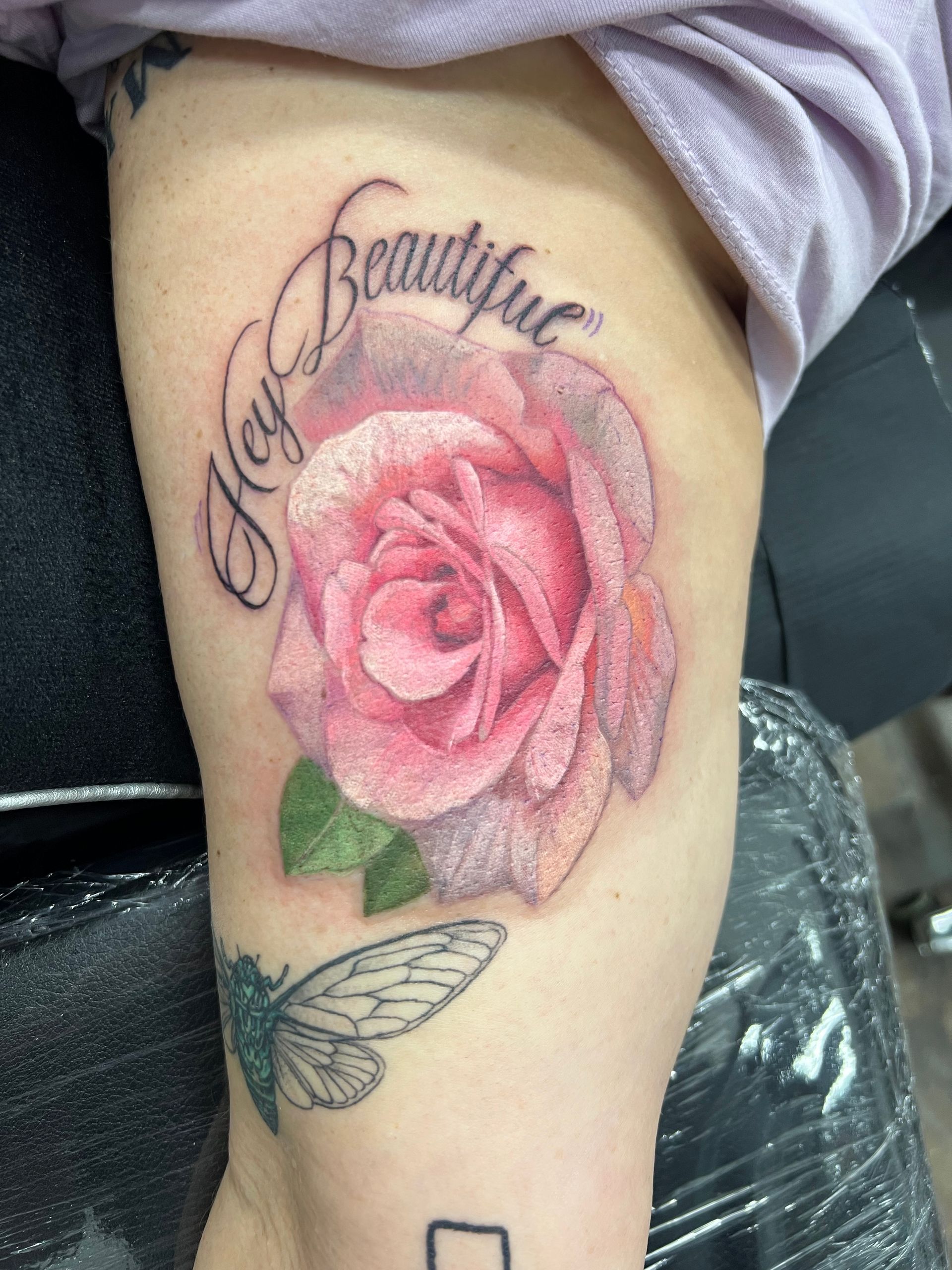 Tattoo of a pink rose with the words