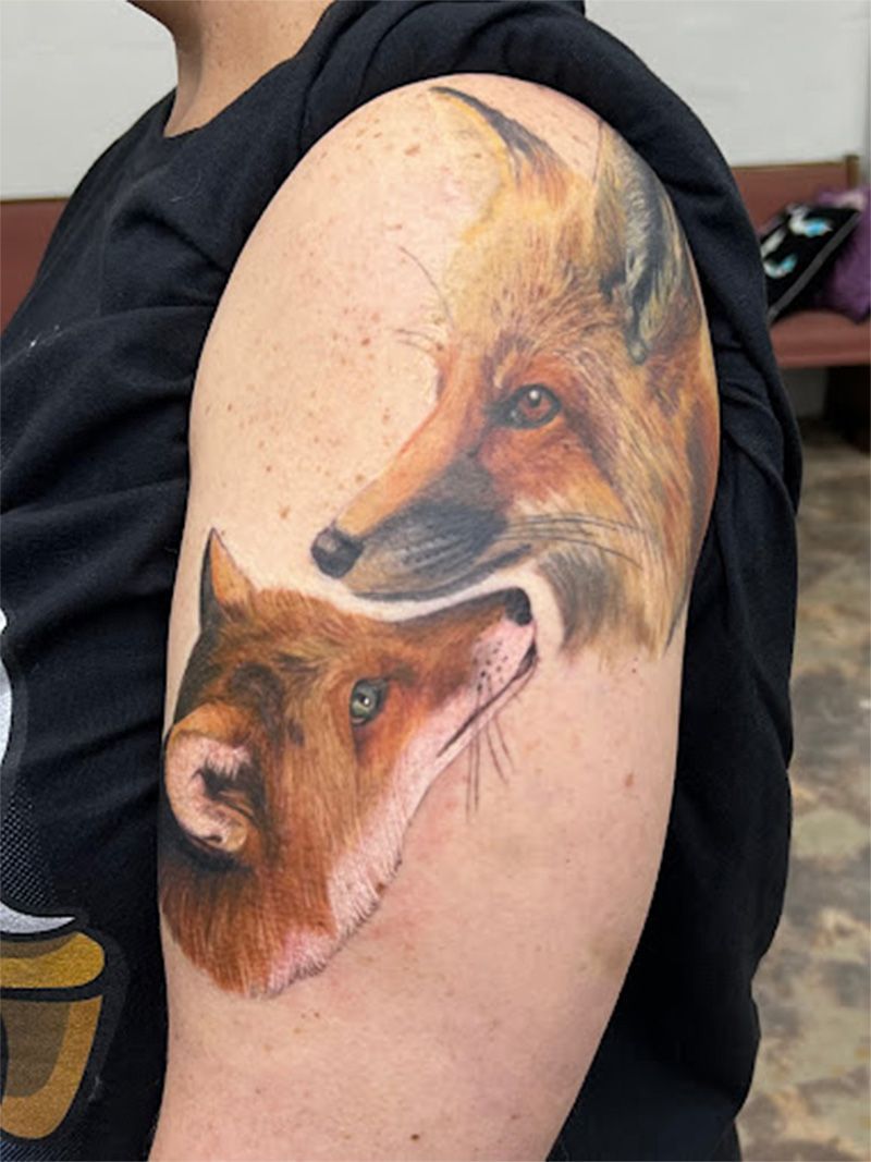 A man has a tattoo of two foxes on his arm.