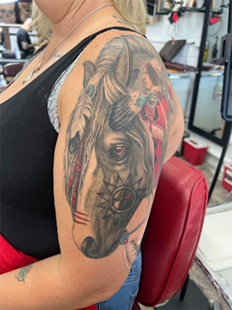 A woman has a tattoo of a horse on her arm.