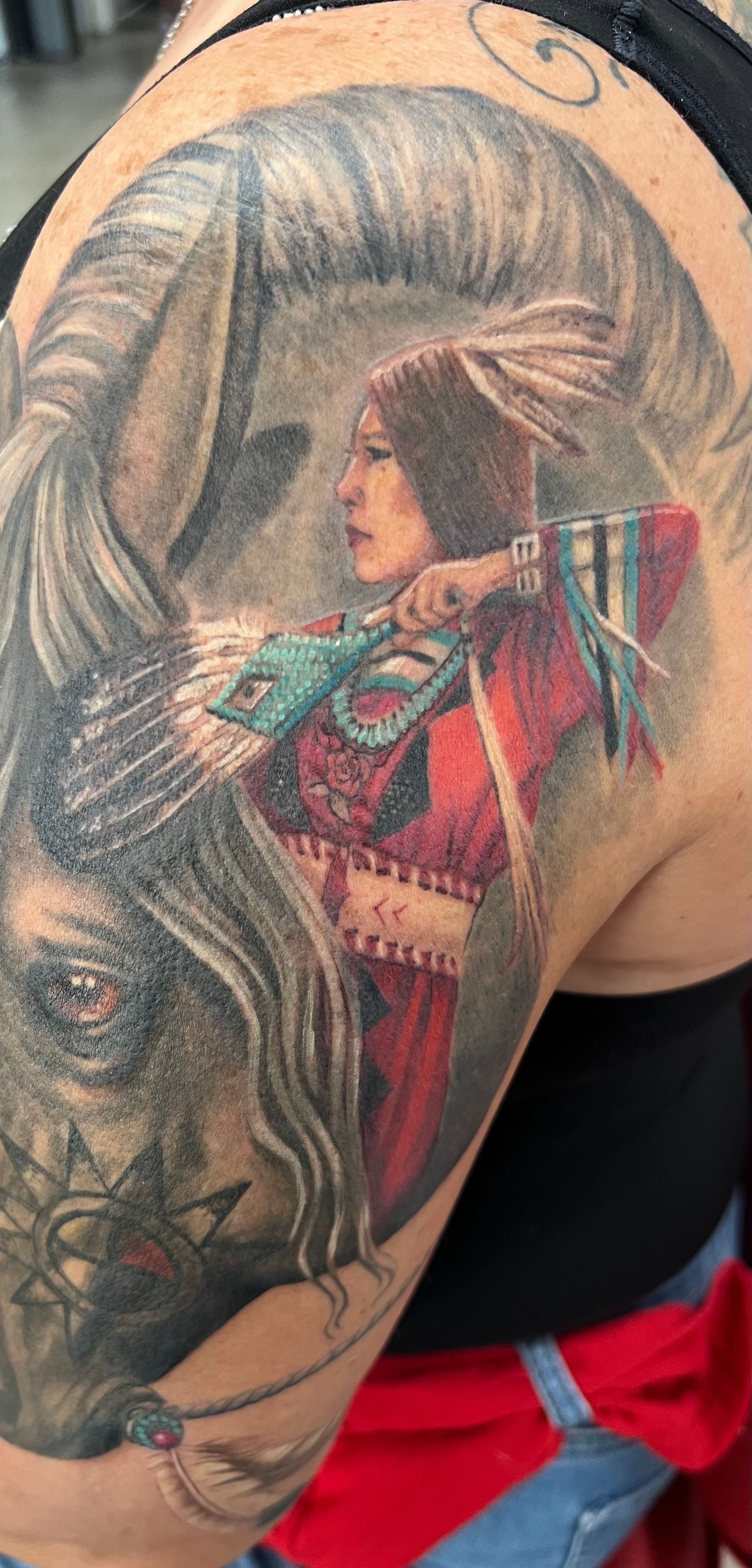 Tattoo of a Native American woman holding a spear with a horse in the background.