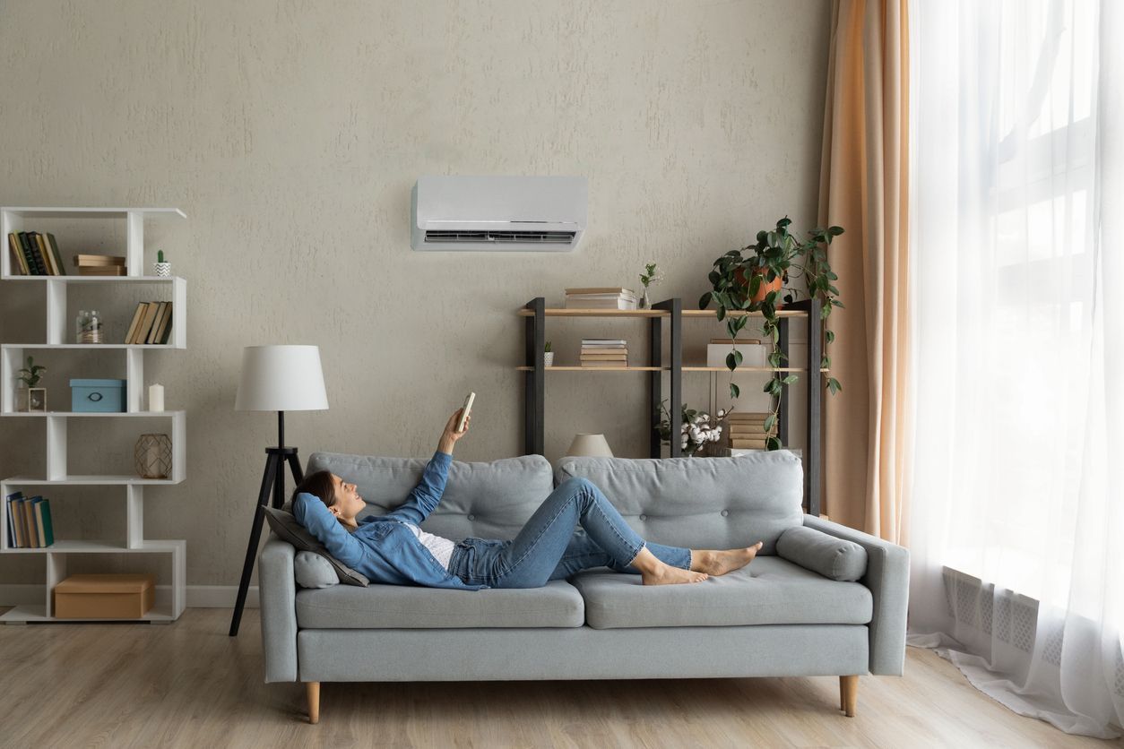 a woman is laying on a couch in a living room holding a remote control .
