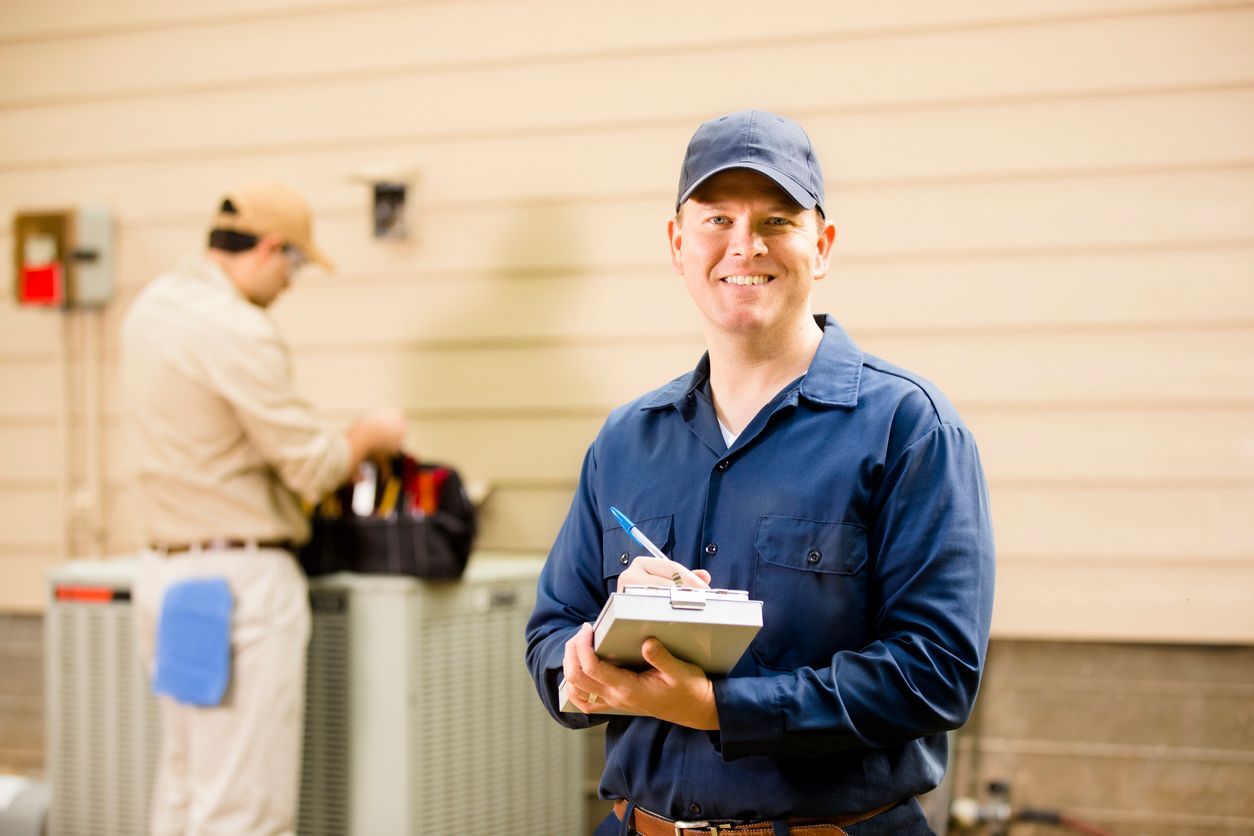 a man is standing in front of an air conditioner holding a clipboard .