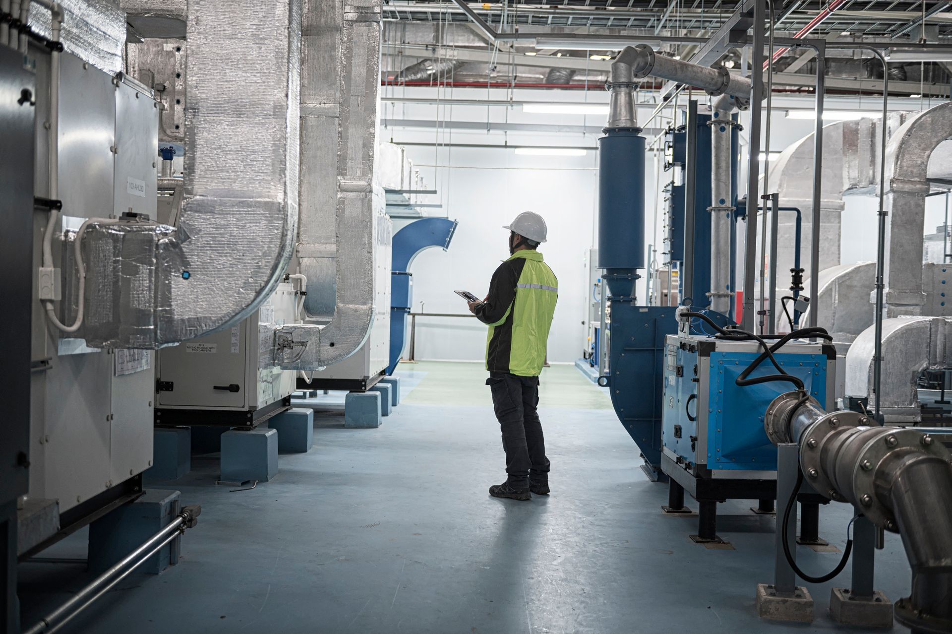 Commercial HVAC technician inspecting industrial piping and mechanical systems in Houston, Texas.