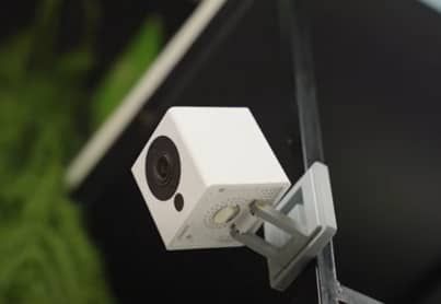 A white cube security camera is attached to a metal pole.