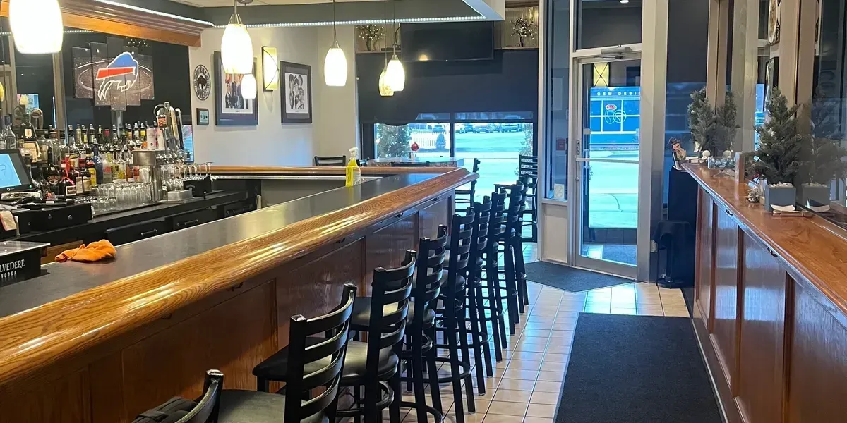 Bar interior with wooden bar, stools, and a glass door.