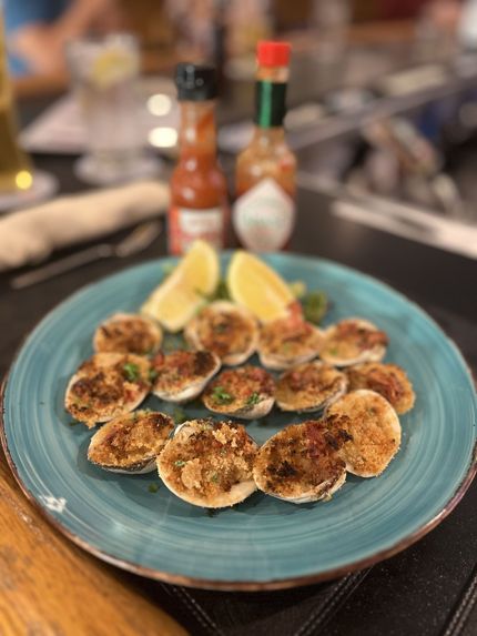 Clams in a buffet tray, garnished with green herbs.