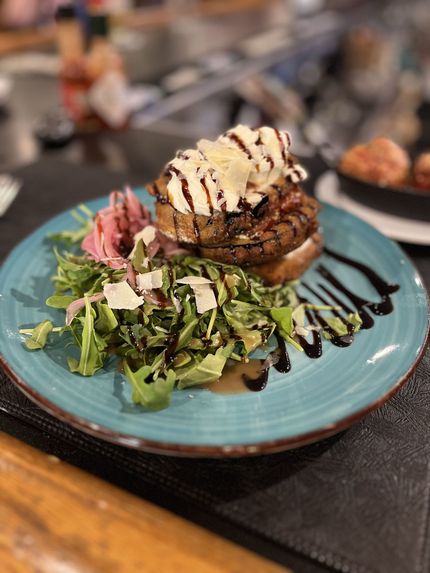 Salad with sprouts, pomegranate seeds, and toasted seeds in a dark bowl.