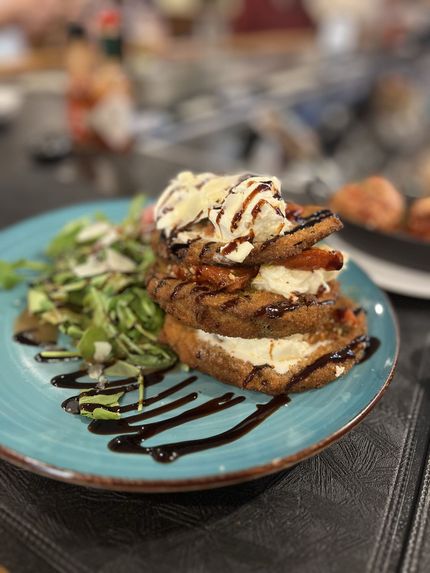 Caesar salad with bacon crumbles, dressing, and grilled bread on a white plate, marble surface.