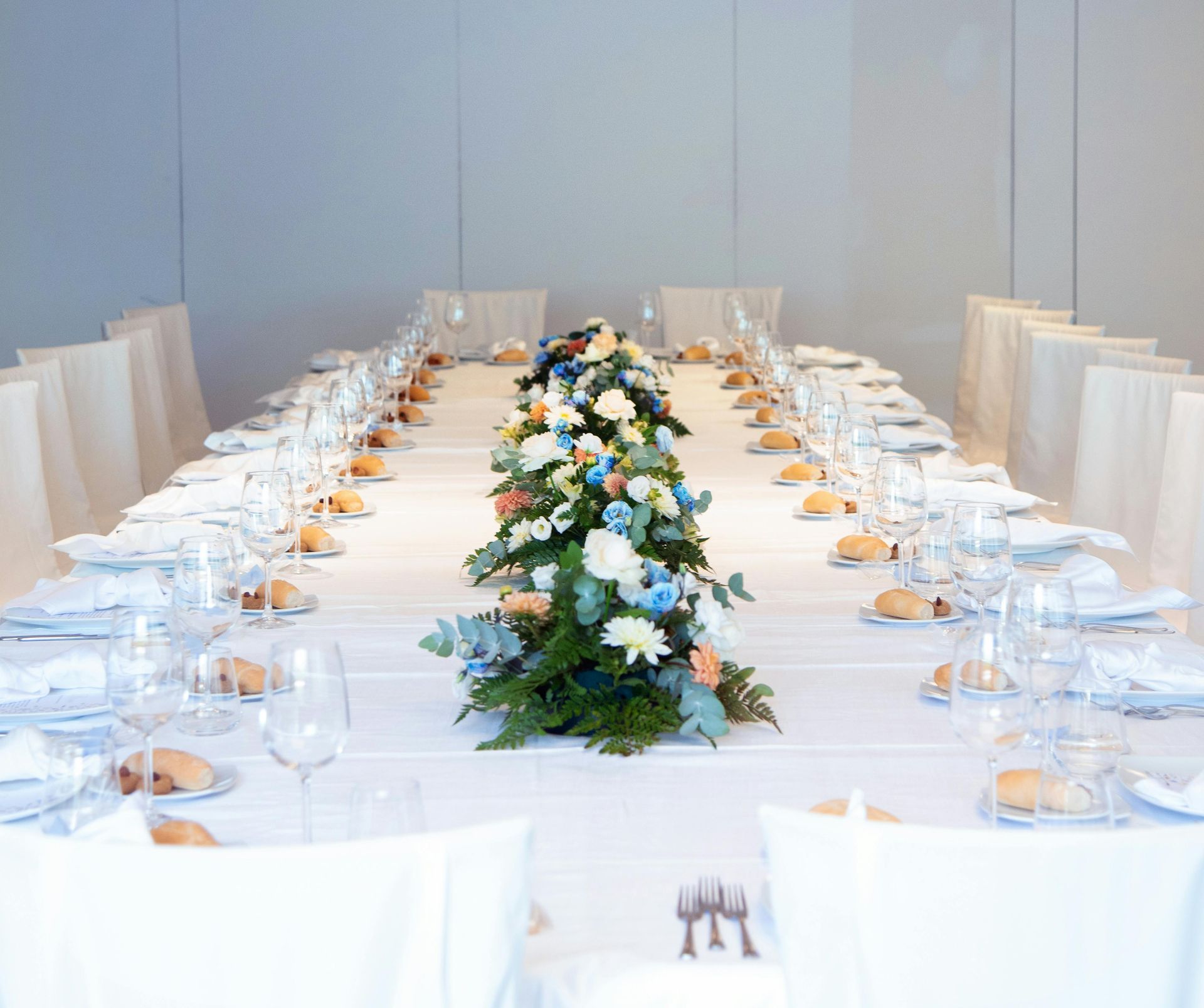 Long formal dining table set for a celebratory meal, centered by a floral arrangement.