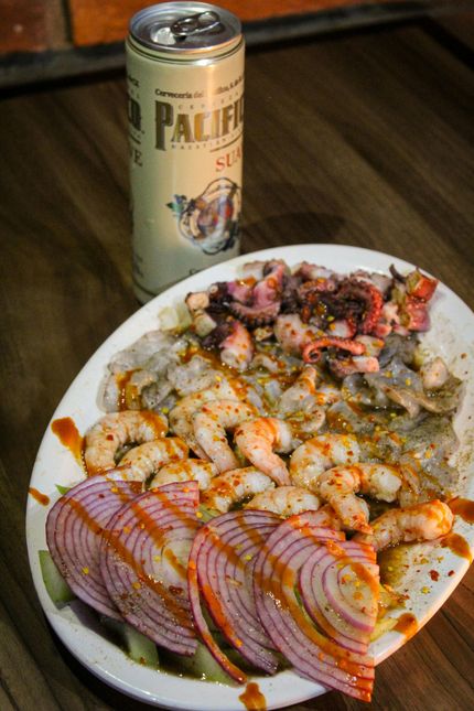 Plate of seafood ceviche with red onion and Pacifico beer can.
