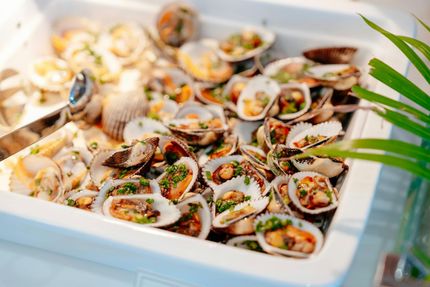 Clams in a buffet tray, garnished with green herbs.