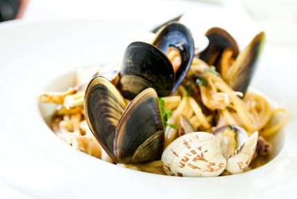 Pasta dish with mussels and clams in a white bowl.