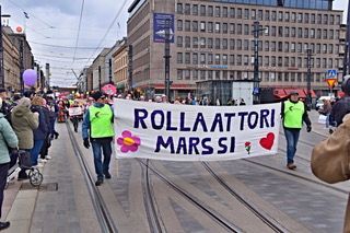 Ihmiset marssivat kantaen banderollia