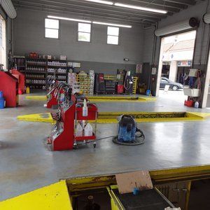 A man is working on a car on a lift in a garage.