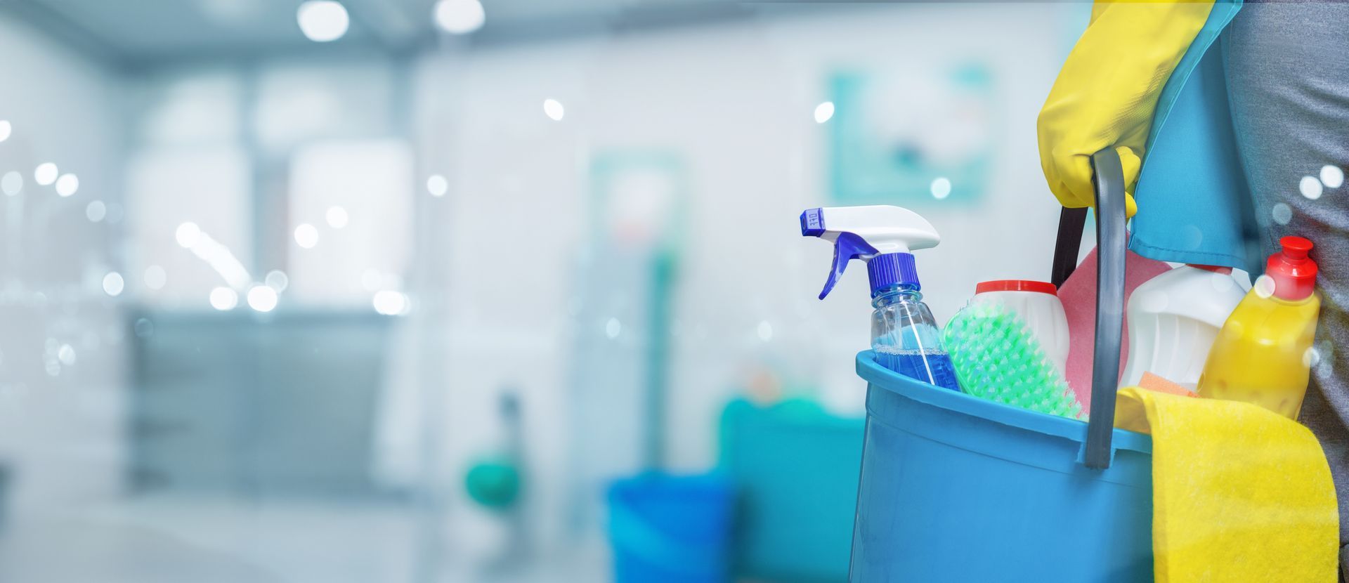 Three people in blue shirts, one with a rolling vacuum, walk towards a house on a sunny day.