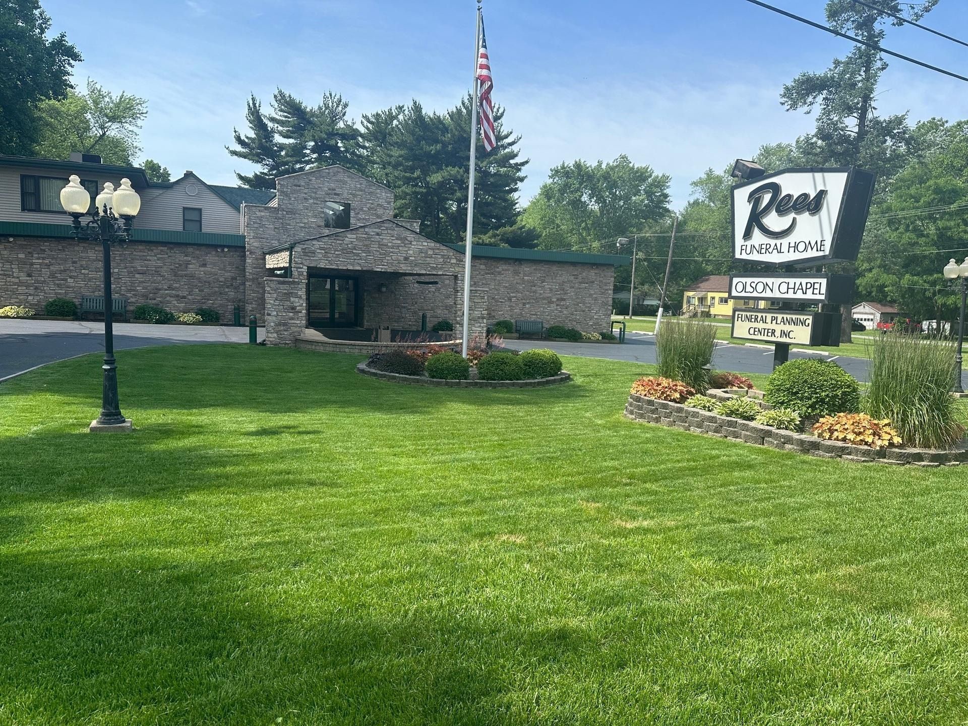 Building with sign reading "Rose Restaurant" and American flag, on grassy lawn.