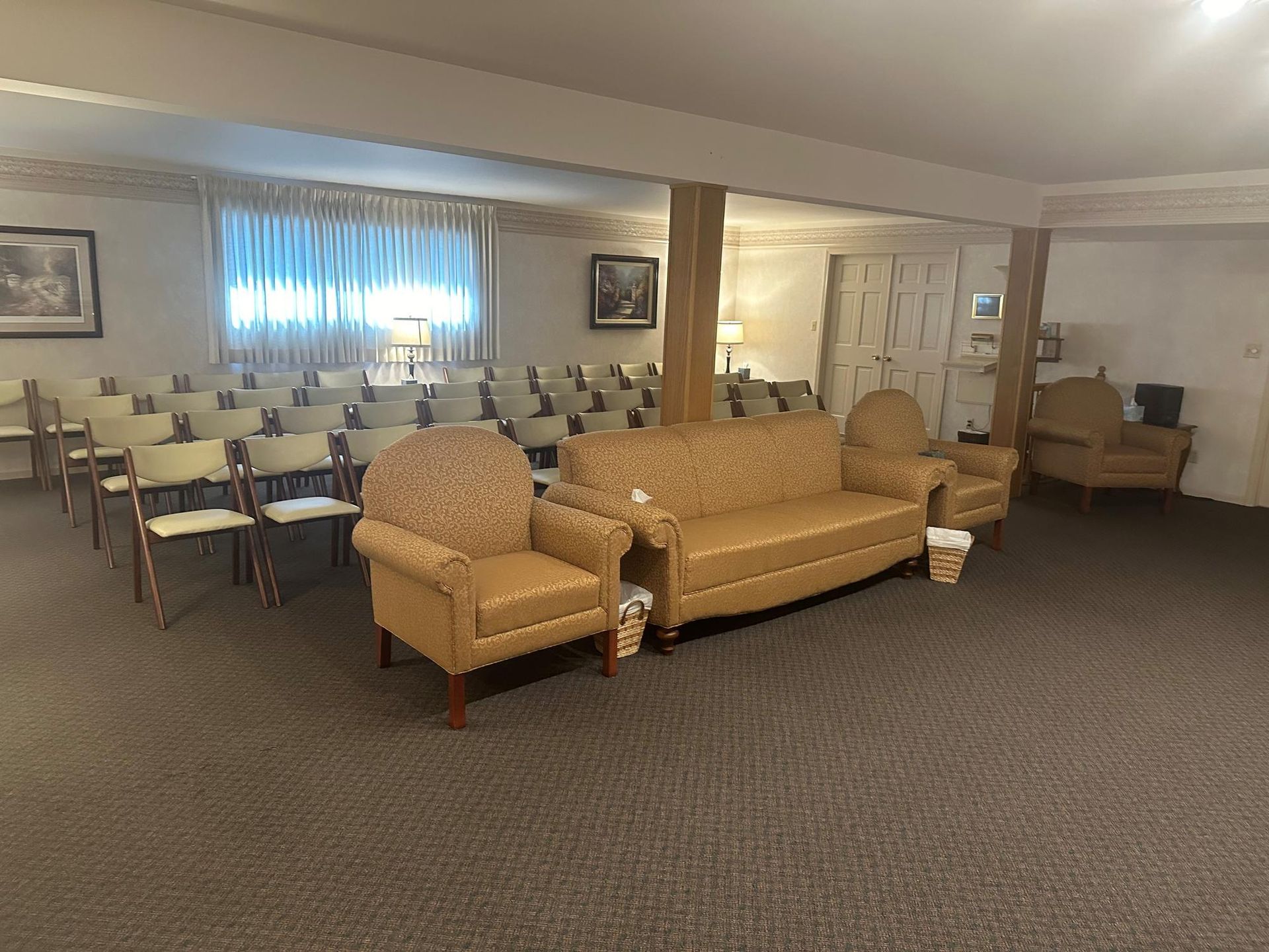 Interior view of a room with chairs set up for a gathering, along with couches and armchairs.