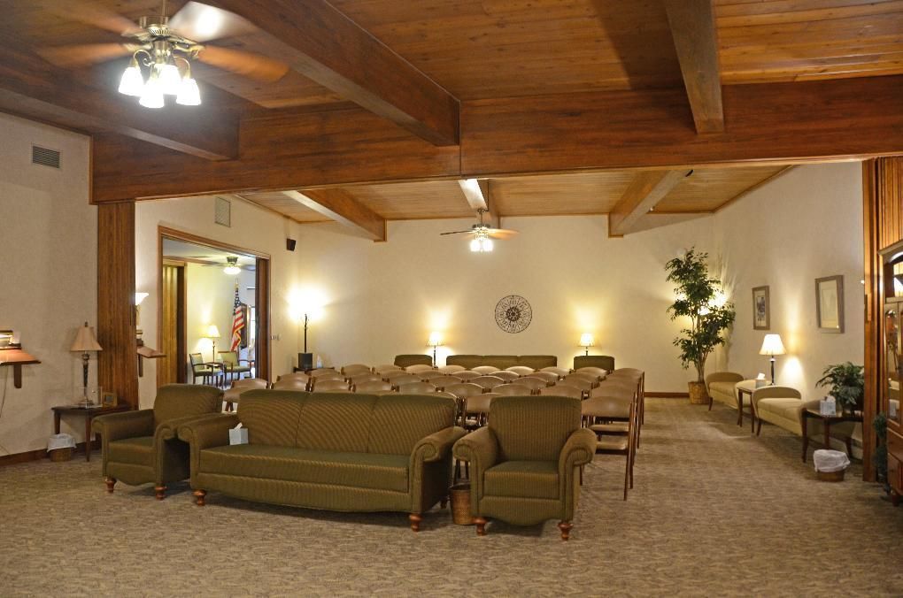 A spacious, well-lit room with seating arranged for a gathering, possibly a funeral home.