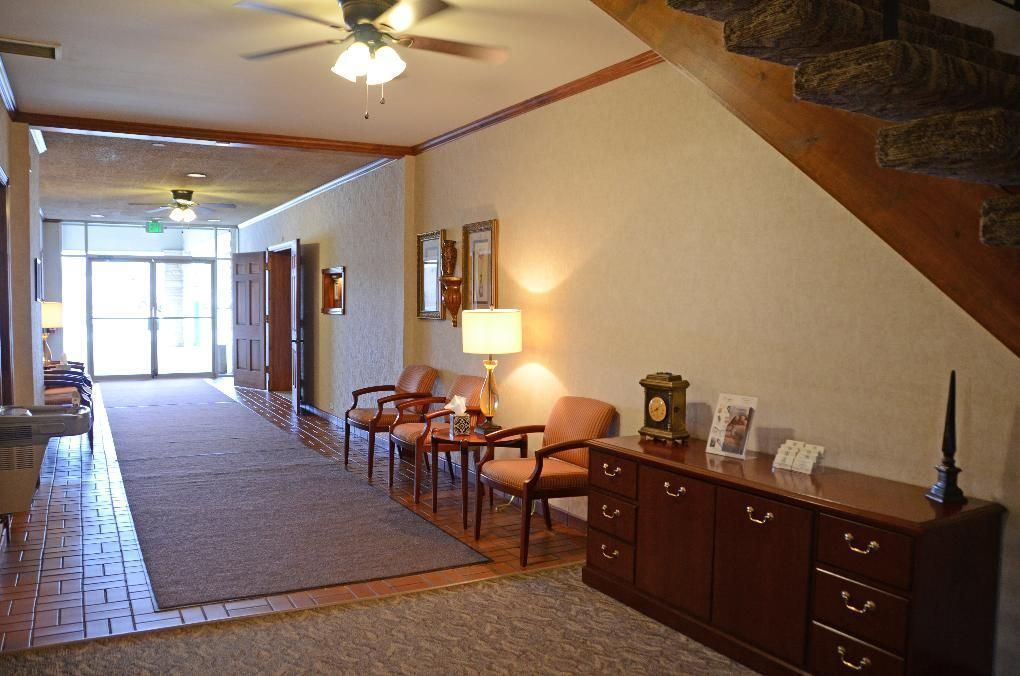 Hallway with seating, wooden cabinets, and staircase. Beige walls and brown flooring.
