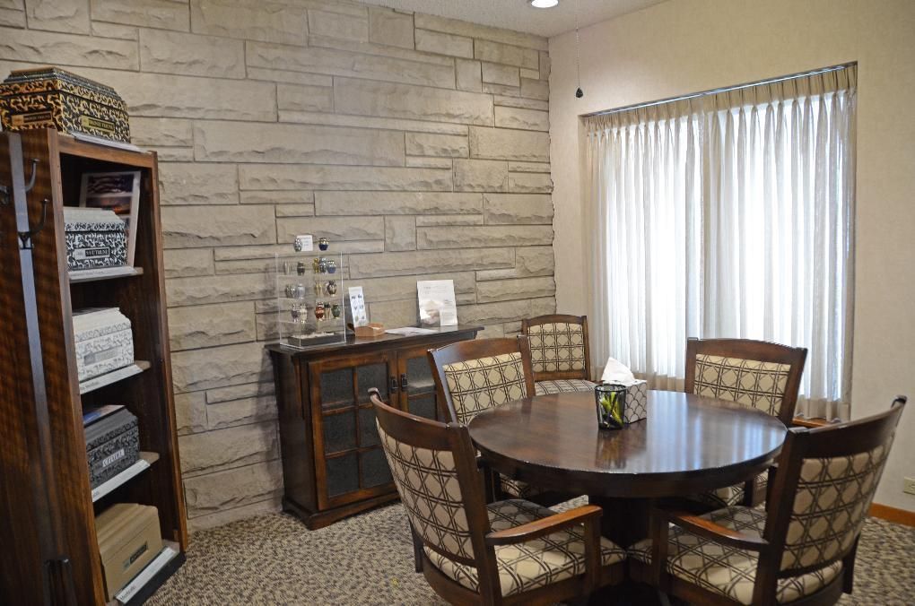 A room with a round table and chairs, a cabinet, and a stone-like accent wall.