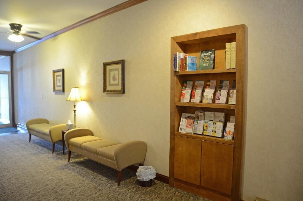 Hallway with a wooden bookshelf, seating, artwork, and a wastebasket.