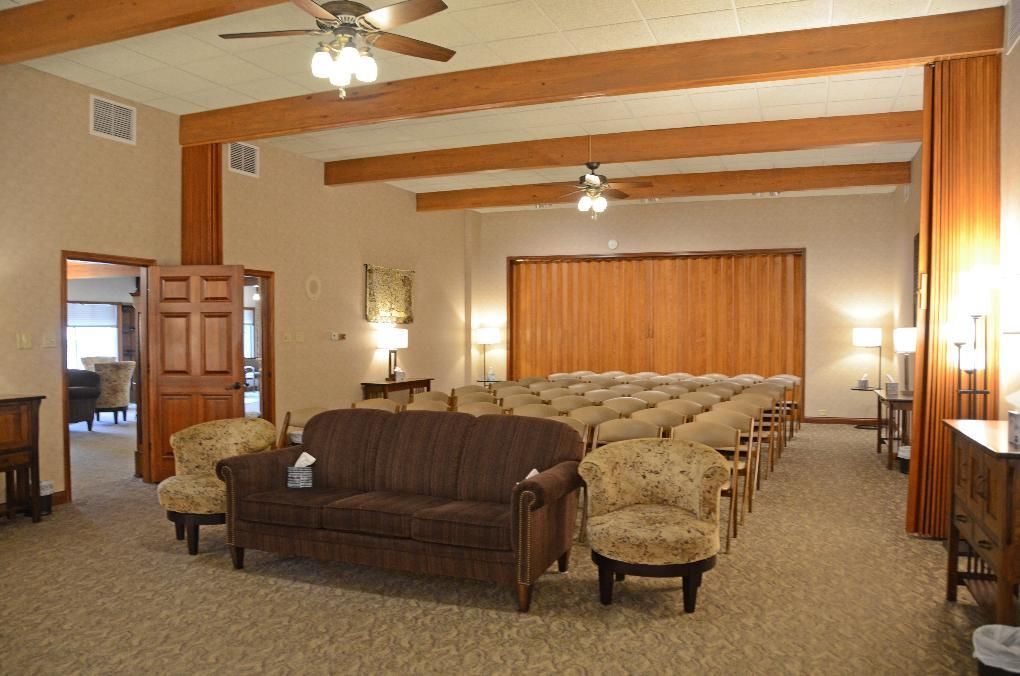 Funeral home interior with seating, wood accents, and rows of chairs.