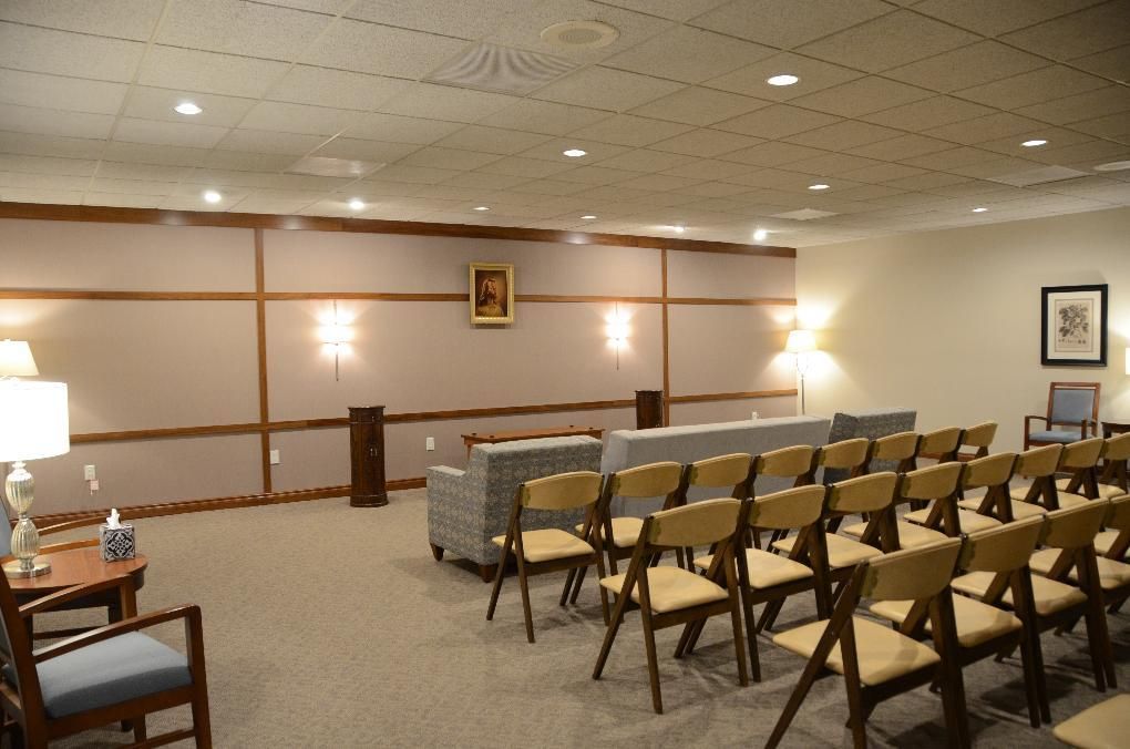 Funeral home interior with seating and memorial display.