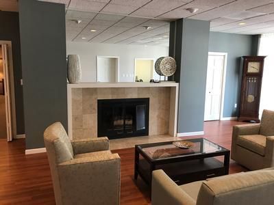 Living room with fireplace, mirrored wall, wood floors, and neutral-toned furniture.