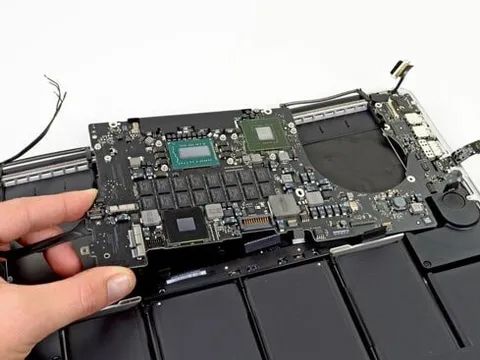 A Person Is Holding The Motherboard Of A Laptop Computer