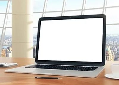 A laptop computer with a white screen is sitting on a wooden desk.