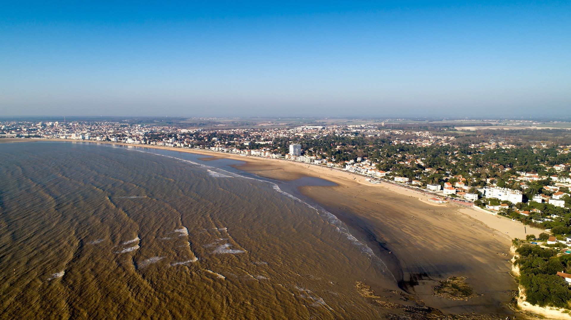 Une vue aérienne d'une plage avec une ville en arrière-plan.