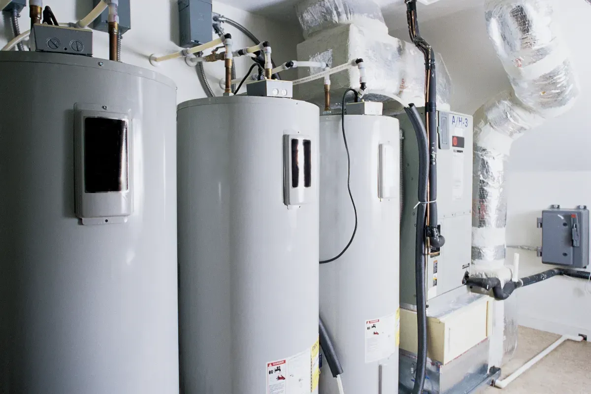Three water heaters and HVAC system in a utility room.