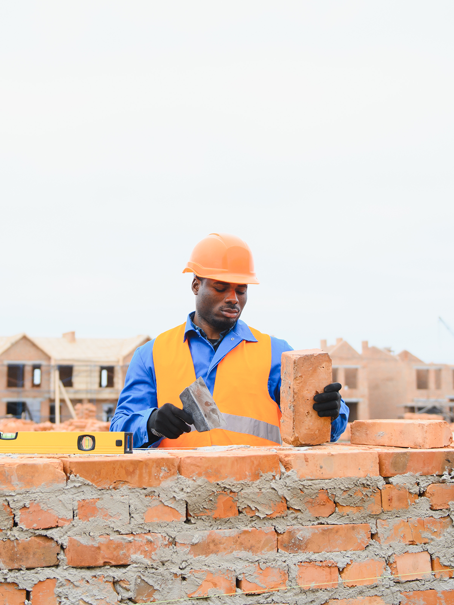 A construction worker is laying bricks on a wall.