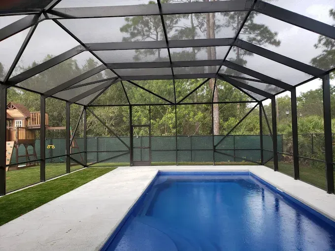 Pool enclosed by a white-framed screen structure with a partially visible pool.