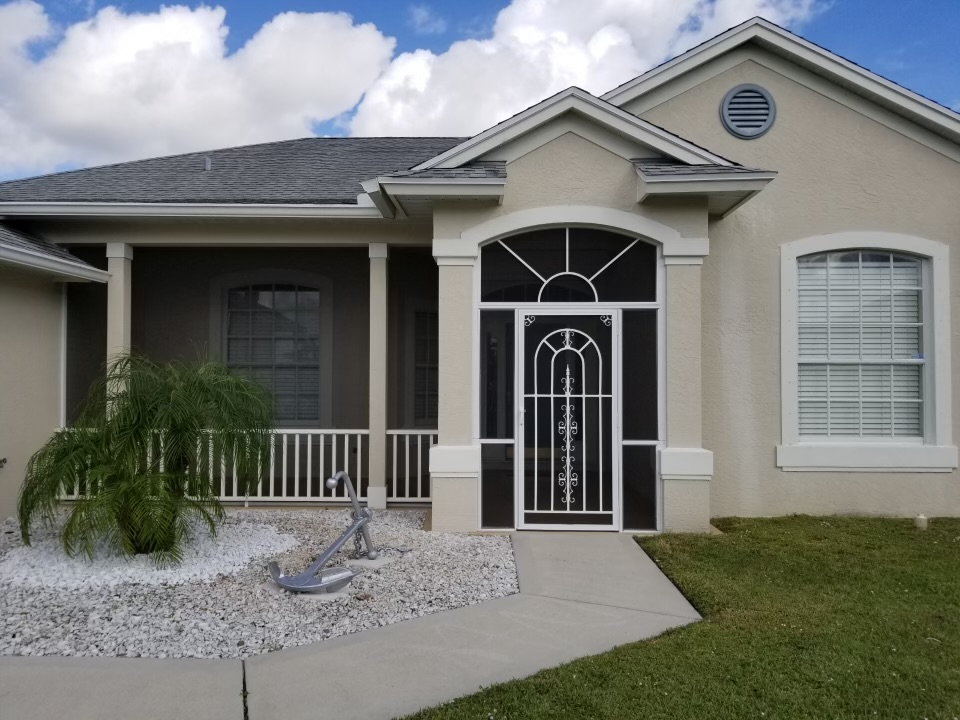 Beige house with porch, screen door, and white gravel landscaping.