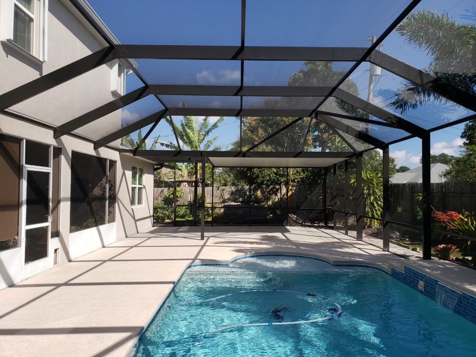 Indoor swimming pool with clear roof and walls, blue water, and decorative tiling.