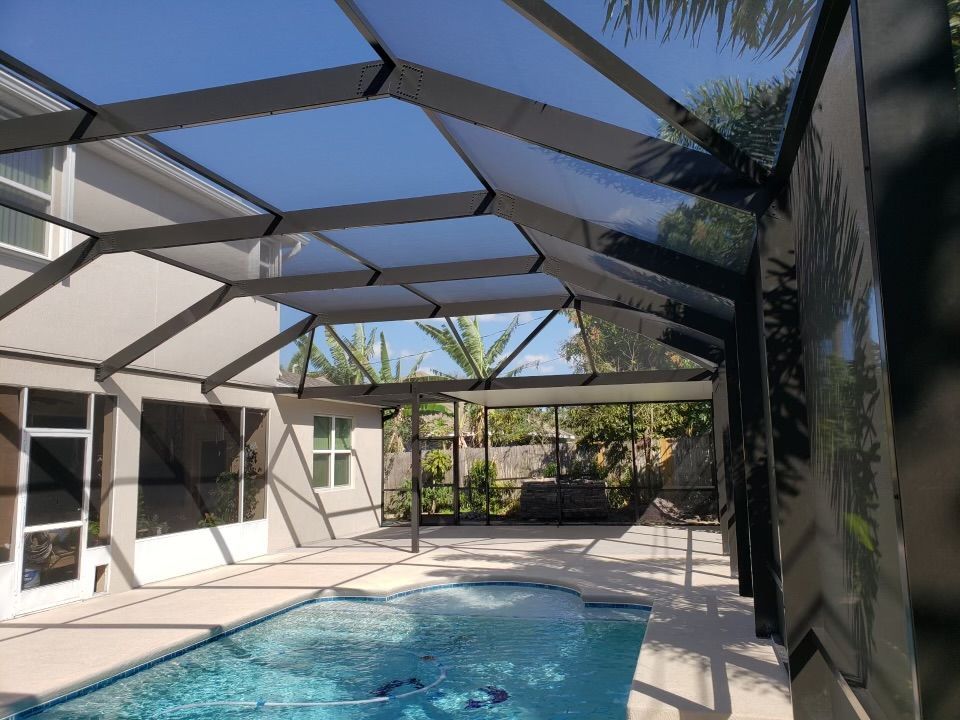 Pool enclosure with a screened roof and walls; outdoor view.