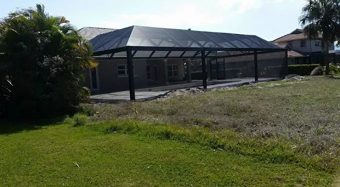 Black screened-in patio enclosure attached to a house; grass and yard in foreground.
