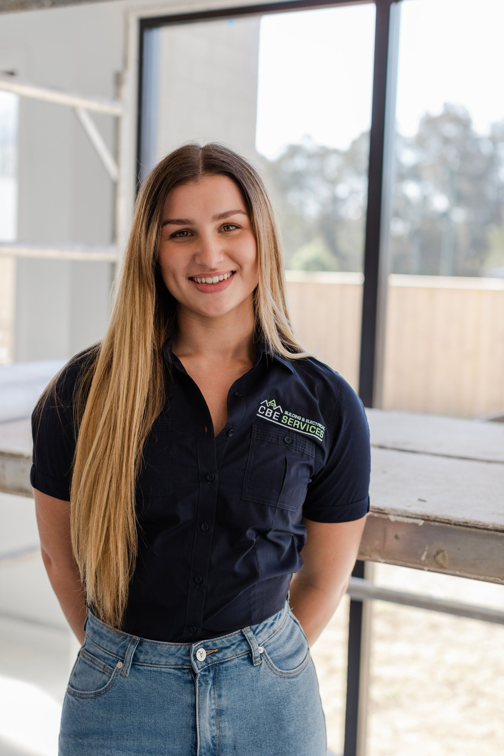 A woman in a black shirt and blue jeans is standing in front of a window — Custom Home Builders in the Hunter Valley