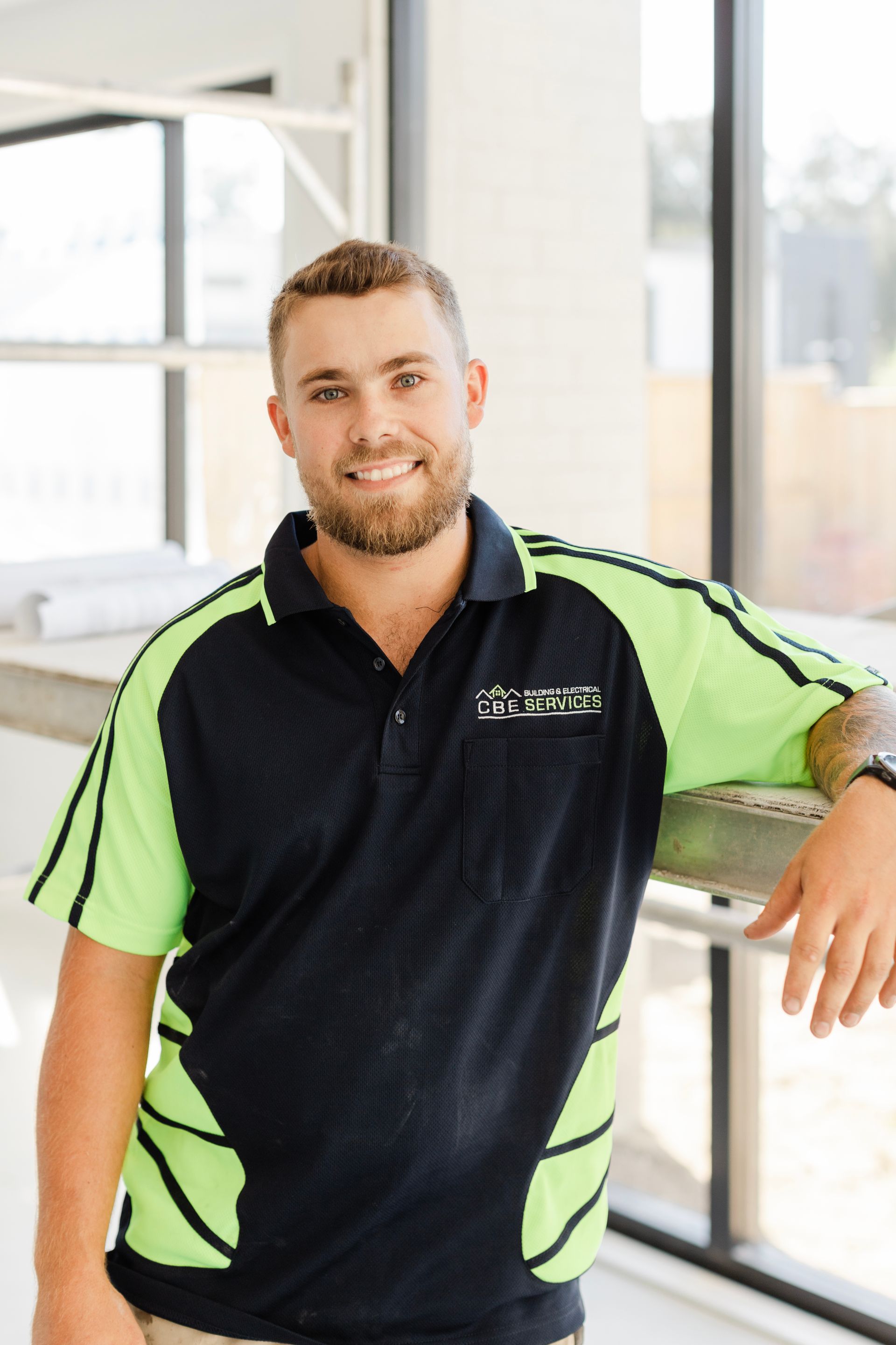 A man in a black and neon green polo shirt is standing in front of a window — Custom Home Builders in the Hunter Valley