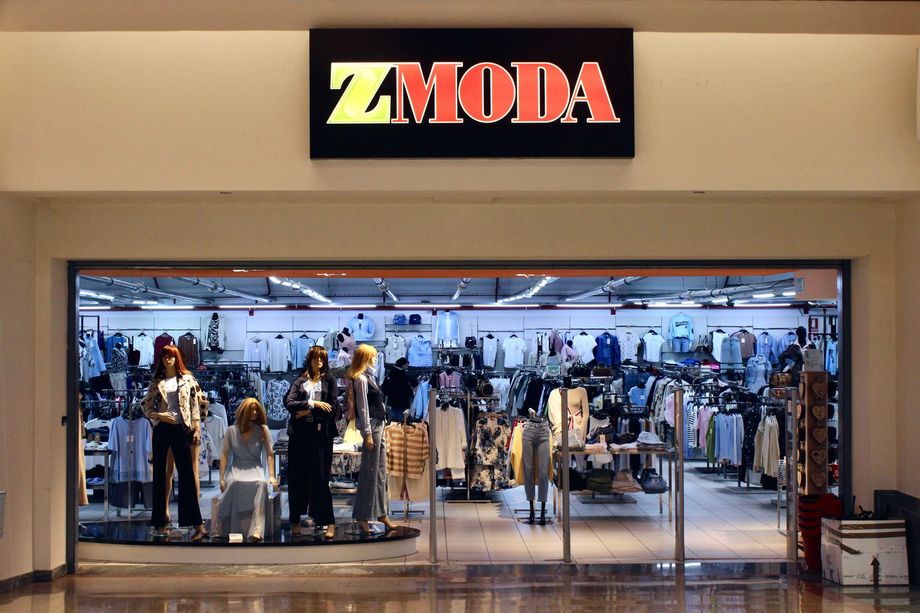 Vetrina del negozio di abbigliamento ZMODA all'interno di un centro commerciale, con manichini in esposizione e appendiabiti all'interno.