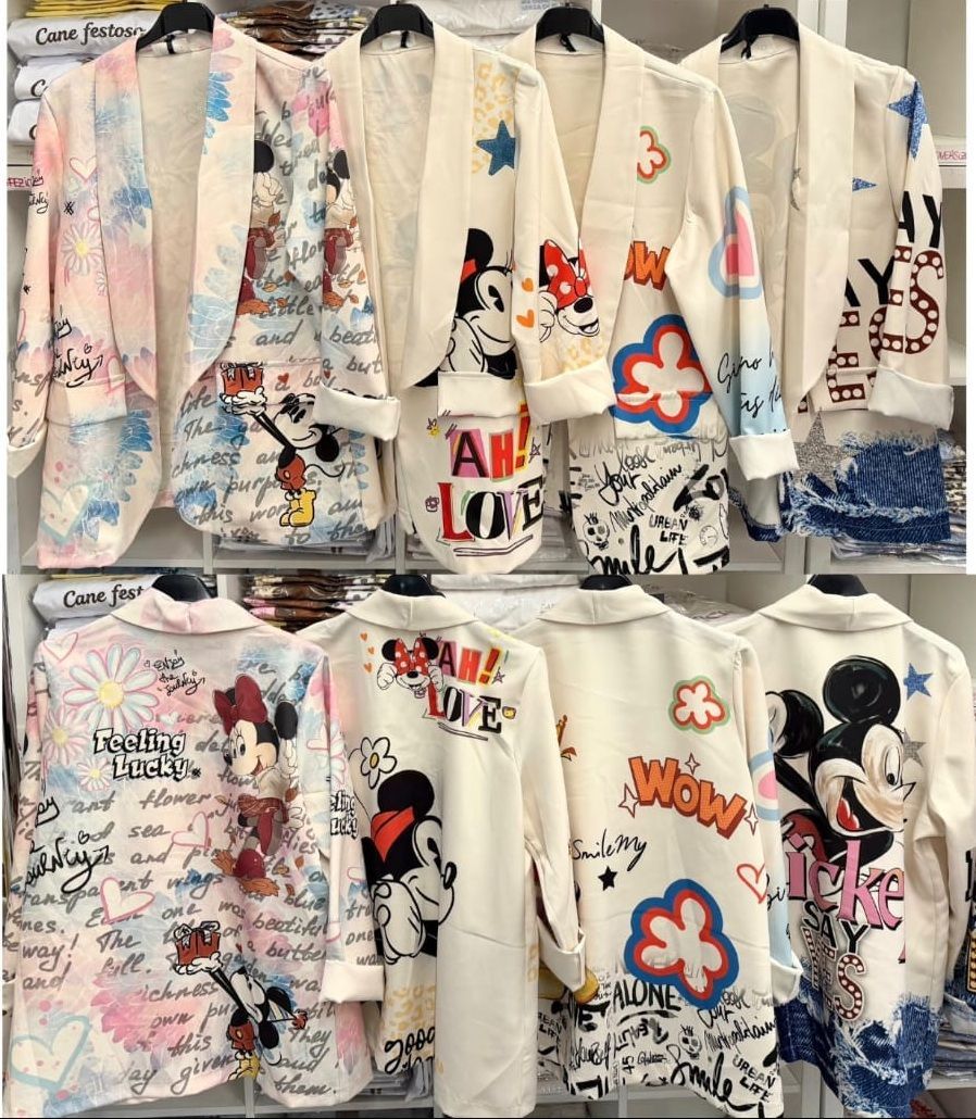 In un negozio di abbigliamento, un espositore con diversi modelli di jeans e camicie in denim appesi a delle grucce.