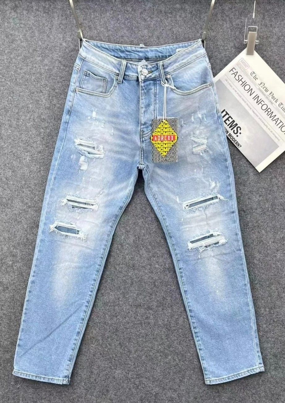 Jeans strappati azzurri con etichetta pendente su sfondo grigio