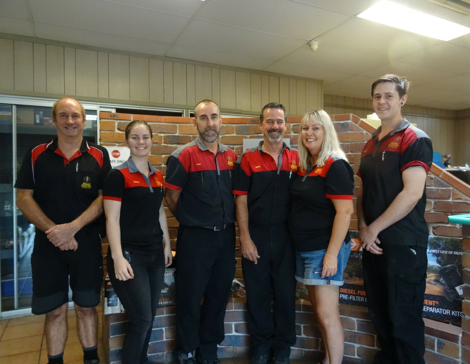 A group of people are posing for a picture in front of a brick wall.