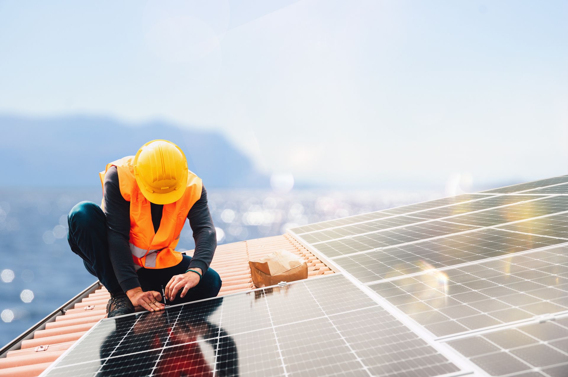 A solar technician on a roof fixing a solar panel.